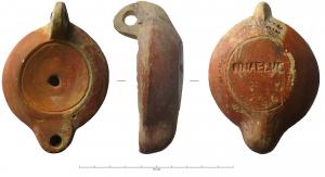 LMP-42199 - Lampe à bec rond : NNAELVCterre cuiteLampe moulée, à anse perforée, marquée de deux sillons. Réservoir circulaire à profil biconvexe assymétrique. Bandeau penché vers l'extérieur; disque lisse, en cuvette limitée par deux sillons concentriques. Bec arrondi limité, par un trait droit, repose sur le rebord du réservoir. Base circulaire plate en léger relief limitée par un sillon, marque en creux NNAELVC. Engobe rouge orangé sur toute la lampe.