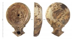 LMP-42218 - Lampe à bec angulaire à volutes simples : Couronne de pampresterre cuiteLampe moulée à bec triangulaire à deux volutes simples se poursuivant sous le bec. Sans anse. Disque en profonde cuvette, limité par trois sillons concentriques. Bandeau étroit penché vers l'intérieur. Réservoir circulaire de profil tronconique. Présence d'un trou d'évent sur le bec. Base en anneau plat. Décor : Couronne de pampres.