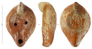 LMP-42372 - Lampe de transition, Atlante VII A 2 : Vase eucharistiqueterre cuiteLampe moulée à bec allongé et grand disque entourés par un bourrelet. Anse verticale pleine moulée avec la lampe. Bandeau guilloché à l'extérieur et orné de trois sillons déterminant quatre bourrelets concentriques dont l’externe représente deux grosses pastilles, faites de trois anneaux concentriques chacune et qui flanquent le départ du canal. Palme dans l'axe du canal, gravée avant  cuisson. Réservoir ovoïde de profil biconvexe. Base plate limitée par deux anneaux plat souligné par deux sillons rejoignant l'anse avec au centre un chrisme bouclé a droite, deux palmes obliques au départ de l’anse. Le dessous du bec porte un riche décor gravé avant cuisson : un chrisme entre deux palmes verticales et deux palmes obliques. Décor : Vase eucharistique.