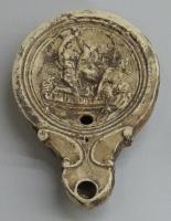 LMP-42399 - Lampe Loeschcke IV : scène érotiqueterre cuiteLampe à bec en ogive, encadré de volutes ; disque concave, limité par trois sillons, orné d'une scène érotique : homme et femme sur un lit à pieds moulurés et draps rayés, la femme adossée à une autre assisie au bord du lit, regardant la scène. Argile jaune clair, engobe brune; base plate.