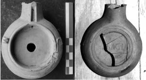 LMP-42487 - Lampe de firme : HERACLterre cuiteLampe à bec en ogive et canal de bec; disque lisse, trois ergots en relief sur l'épaule. Argile rouge, sans engobe ; sous la base, marque moulée HERACL.