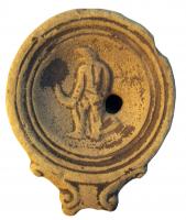 LMP-4304 - Lampe Loeschcke IV : Gladiateurterre cuiteLampe à bec à enclume et volutes latérales; disque orné d'un gladiateur vaincu, bouclier à terre et tête baissée. Argile noisette, engobe orange foncé à marron foncé; base plate entourée d'un anneau en relief.