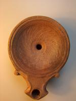 LMP-4310 - Lampe Loeschcke IV : Rosetteterre cuiteLampe à bec à enclume et volutes latérales; disque orné d'une rosette formée de S en relief. Argile noisette, engobe orange foncé à marron foncé; base plate entourée d'un anneau en relief.
