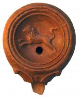 LMP-4315 - Lampe Loeschcke IV : Lion bondissant à gaucheterre cuiteLampe à bec à ogive et volutes latérales; disque orné d'un lion courant vers la gauche. Argile noisette, engobe orange foncé à marron foncé; base plate définie par un cercle incisé; bec cassé.