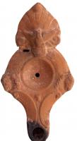 LMP-4426 - Lampe Loeschcke III tardive : POYPLIOYterre cuiteLampe à long bec rond accosté de volutes. Disque vierge; épaule décoré de protomes de chevaux. Anse à réflecteur ornée de palmette et aigle. Argile beige clair, engobe orange; base plate. Marque POYPLIOY en lettres grecques incisées.
