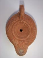 LMP-4457 - Lampe Loeschcke IV tardive terre cuiteLampe à long bec rond et volutes internes. Disque vierge, épaule décorée d'une frise végétale. Argile orange, engobe orange; base plate.