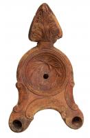 LMP-4462 - Lampe Loeschcke III à deux becs : Couronneterre cuiteLampe à double long bec à ogive et volutes internes. Disque décoré d'une couronne d'olivier. Argile noisette, engobe brun; base plate. Anse à réflecteur triangulaire avec feuille de chêne.