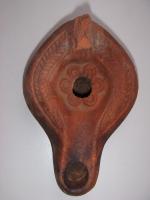 LMP-4578 - Lampe Hayes I : Rosetteterre cuiteLampe africaine tardive classique, piriforme. Médaillon orné d'une rosette. Epaule de motifs en feuille de palme. Argile orange, engobe orange. Anse à l'arrière.