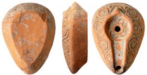 LMP-5011 - Lampe en forme d'amandeterre cuiteAppendice de préhension pyramidal en reliel. Réservoir en forme d'amande à canal rehaussé et de profil biconique. Petit disque au décor géométrique et percé d'un petit trou d'alimentation. Il est entouré par un bourrelet qui se poursuit sur le canal. Bec arrondi non saillant.  Décor de cercles en relief, contenant des éléments géométriques  sur le bandeau.
Base plate non délimitée.
