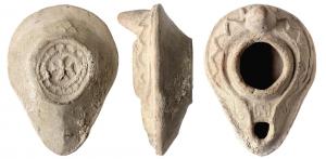 LMP-5035 - Lampe syro-palestinienne à canalterre cuiteAnse en tenon conique. Réservoir piriforme de profil biconique. Motif en dents de scie en relief sur le bandeau se terminant en volute au niveau du bec Grand trou d'alimentation bordé par un bourrelet, entouré par une gouttière. Le bourrelet qui la limite se poursuit de long d'un canal sur le bec portant un carré décoratif. Base circulaire plate entourée par un bourrelet en relief enfermant une croix pattée entourée d'une couronne de ponts en relief.
