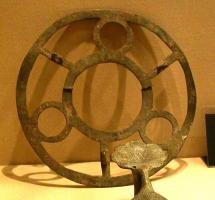 LUS-5004 - LustrebronzeLustre constitué d'un simple anneau (plaque épaisse) ajouré d'orifices circulaires pour l'insertion de lampes en verre, ouvertures circulaires intercalées de simples ajours trapézoïdaux; suspension à chaînettes, utilisant éventuellement des éléments allongés en tôle et percés aux extrémités.
