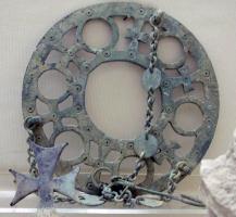 LUS-5009 - LustrebronzeLustre constitué d'un simple anneau (plaque épaisse) ajouré d'orifices circulaires pour l'insertion de lampes en verre, ouvertures circulaires intercalées d'ajours trapézoïdaux occupés par des croix, en simples X ou à branches pattées parfois marquées d'ocelles; suspension à chaînettes, utilisant éventuellement des éléments allongés en tôle et percés aux extrémités.