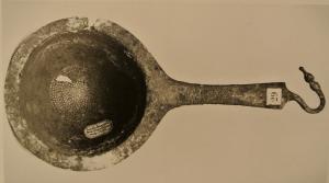 PAS-3011 - Passoire à manche coulébronzePassoire à manche plat, coulé, terminé par un crochet en forme de tête animale; vasque arrondie sans ressaut; à l'opposé du manche coulé, anse coulée et terminée par un bouton quadrangulaire apati.