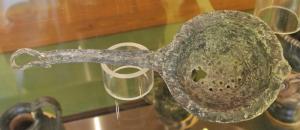 PAS-3014 - Passoire à manche couléplombPassoire à manche plat, coulé, terminé par un crochet en forme de tête animale; vasque arrondie sans ressaut; à l'opposé du manche coulé, anse coulée et terminée par un bouton quadrangulaire apati.