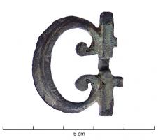 PLB-4073 - Boucle de cingulum type AislingenbronzeBoucle de ceinture dont les deux extrémités se replient en crosse à l'intérieur ; l'ardillon en forme de fleur de lis (ou orné d'un motif quadrangulaire ajouré) vient s'insérer entre ces crosses et comprend deux excroissances qui en épousent les formes ; axe en fer. Cette boucle s'articule à une plaque rectangulaire équipée de trois robustes charnons encadrant ceux de la boucle et l'ardillon.