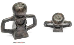 SCH-4029 - Suspension de caisse de charbronzeSuspension de caisse de char constituée d'une douille en forme d'autel, de section carrée avec base et couronnement moulurés, guirlande en façade, surmontée d'une sphère aplatie (fruit ?) avec au sommet un fleuron simplifé ; de part et d'autre du corps central, robustes crochets angulaires en forme de doigts.