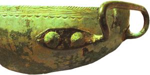 SPL-1002 - Puisoir à anse rivetéebronzeRécipient  hémisphérique,sans fond plat, à bord rentrant, muni d'une seule anse horizontale rivetée, parfois torsadée ; décor alterné de lignes de dents de loup, d'incisions obliques et de lignes parallèles.