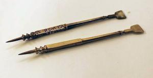 STY-4130 - Stylet inscritbronzeStylet en bronze comportant une pointe fine, puis un fût séparé de la pointe par une série de moulures destinées à faciliter la préhension (la partie basse de ce fût, de section carrée, porte une inscription répartie sur les quatre faces, généralement un aphorisme amoureux), avant une palette rectangulaire allongée.