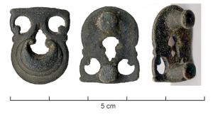 APH-4090 - Applique de harnaisbronzeApplique en forme de lunule soulignée de plusieurs bandes, se rejoignant au sommet en un motif ajouré de peltes ; au revers, deux tenons.