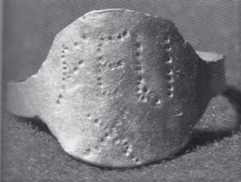 BAG-4417 - Bague inscriteorBague en tôle, jonc rubané, large chaton ovale portant une inscription ponctuée.