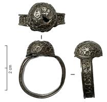 BAG-7029 - Bague à chaton métallique hémisphériqueargentAnneau rubané, orné d'un motif filigrané continu, des groupes d'annelets séparés par des traits obliques, ouvert et soudé sous le chaton. Ce dernier est une demi-sphère creuse, ornée de trois niveaux d'annelets séparés par des filets, le tout également en filigranes d'argent.