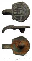 BCC-5041 - Ardillon bronzeArdillon coulé avec en-dessous la bélière d'articulation sur sa plaque-boucle ; plaque trapézoïdale plate, à décor incisé : monogramme ?