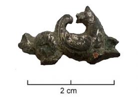 FIB-41456 - Fibule zoomorphe : monstre marinbronzeFibule étamée en forme de monstre marin à deux têtes tournées l'une vers l'autre, stylisé, nageant à droite. Incisions niellées.
