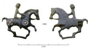 FIB-4341 - Fibule zoomorphe, groupe : cavalierbronzeCheval au galop harnaché et monté par un cavalier ; corps émaillé de disque et de pastilles rondes; barre de sol.