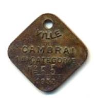 FIS-9007 - Plaque fiscale pour chien : CambraibronzePlaque losangique au sommet percé, avec une inscription moulée : VILLE DE CAMBRAI / 1E CRIE / 1933 et au-dessus de la date, un numéro estampé.