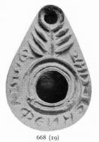 LMP-4175 - Lampe syro-palestinienne tardive (type pantoufle)terre cuiteLampe pantoufle avec inscription grecque sur l'épaule ([[FWS XY Feni pasin kale]]). Au-dessus du bec, un motif en forme de menorah. Bec entouré d'un cercle en relief.