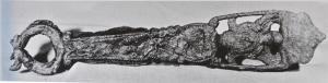 PAS-3013 - PassoirebronzePassoire à manche plat, terminé par une boucle en forme de lyre, ajouré près du récipient d'un motif figuré, à fond découpé.