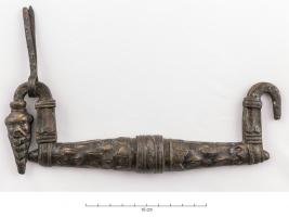 PGM-4012 - Poignée de meublebronzeAnse ou poignée arquée, dont les extrémiéts retombent sur les côtés, chacun d'eux se terminant par une tête de Silène, chauve et barbu.