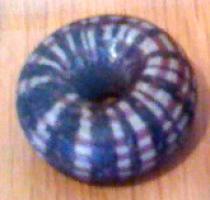 PRL-3513 - Perle annulaire massive : décor de filets spiralés - groupe Haevernick 25verrePerle annulaire massive (D. perforation < D. section) en verre bleu ; décor de damier composé de filets transversaux blancs et spirale concentrique pourpre.
Le diamètre externe est de l'ordre de 20 à 30 mm.