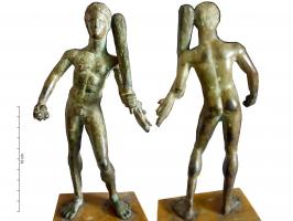 STE-3020 - Statuette : Héraklès - HerculebronzeStatuette de style classique, représentant Heraklès jeune et athlétique en position déhanchée vers la droite. Il tient dans la main gauche la massue reposant sur son épaule, et la léonté enroulée autour de l'avant-bras gauche. Dans sa main droite, trois petits globules représentent les pommes du Jardin des Hespérides.