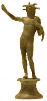 STE-4197 - Statuette : HeliosbronzeStatuette figurant le dieu Hélios, debout, nu, la tête entourée de rayons, la main droite levée vers le ciel. De la main gauche il retient la chlamyde jettée sur son épaule gauche. L'ensemble du corps est déanché vers la droite. Cette statue est posée sur un socle en bobine asymétrique, dont la moulure supérieure porte une rangée d'oves.