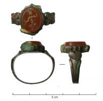 BAG-4174 - Bague à intaille à épaulementsbronzeBague bipartite : jonc légèrement élargi aux épaules, avec un motif en écusson ou foliacé de part et d'autre d'un cabochon serti et rapporté, pour intaille.