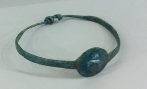 BRC-4098 - Bracelet à médaillon et extrémités nouéesbronzeBracelet à jonc plat, dont la partie centrale est découpée en forme de disque équipé d'un umbo; à l'opposé, extrémités filiformes nouées.