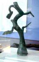 CDL-4002 - CandélabrebronzePetit candélabre en forme d'arbre, à base épaissie ou pourvue d'un tenon pour insertion dans une plaque support ; tronc noueux (parfois en plusieurs segments) avec quelques feuilles plus ou moins dentelées; le sommet est généralement plat et devait supporter un petit plateau, fixé par brasure, sur lequel on posait une ou plusieurs lampes en bronze.