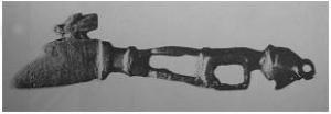 CER-9005 - CernoirbronzePetit couteau à lame courte et large, dos surmonté d'une tête animale; le manche, très ajouré, se termine par une figurine humaine assise, peut-être les bras passés autour des genoux.