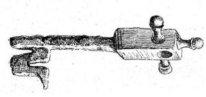 CLE-4115 - Cléfer, bronzeClé à manche de bronze coulé sur la tige en fer, sans doute à mouvement rotatif (?) ; manche parallélépipédique à tête perforée, trois boutons allongés sur les côtés et au sommet du manche.
