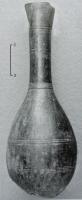 CRU-5012 - Cruche fusiformebronzeCruche à panse ovoïde, col tubulaire étroit et allongé ; anse rapportée ; la panse est ornée de groupes de filets parallèles tracés au tour, pouvant encadrer des motifs curvilignes.