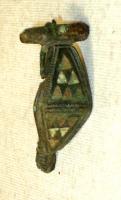 FIB-4117 - Fibule émailléebronzeTPQ : 70 - TAQ : 100Fibule à charnière dont le corps losangique est formé de deux triangles accolés par leur base, avec chacun 3 lignes de petits triangles (disposés 3, 2, 1 : 6 au total) émaillés.