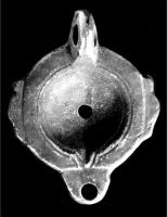 LMP-41549 - Lampe à ailerons et volutes dégénéréesterre cuiteLampe moulée sans anse; réservoir circulaire de profil convexe portant deux ailerons sur l'axe horizontal; bandeau étroit, plat; disque circulaire limité par deux sillons qui se poursuivent jusqu'au bec le long d'un petit canal en V.  Bec long arrondi, à volutes dégénérées. Base circulaire limitée par un sillon. Engobe rouge vif .  