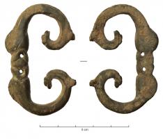 PLB-4054 - Plaque-boucle articuléebronzePlaque-boucle à boucle en D apati, prolongée du côté de la charnière par des crosses; de part et d'autre de l'ardillon, têtes de dauphins affrontées, de style réaliste.