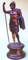STE-4219 - Statuette : Arès - Mars cuirassébronzeLe dieu est barbu, casqué et cuirassé. Debout, il prend appui sur la jambe droite tandis que la gauche est légèrement fléchie. Le bras droit levé s'appuie à une lancé. Le bras gauche, replié ou levé porte une épée, un vêtement ou tient un bouclier.