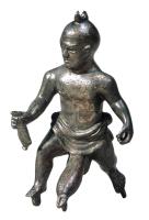 STE-4447 - Statuette : tintinnabulum priapiquebronzeFigurine priapique sous la forme d'un homme à grosse tête (indiquant peut-être un nain), en subligar d'où émerge un sexe démesuré, en érection. L'homme semble marcher en tenant un objet dans chaque main (outre ou balsamaire dans la main gauche ?); au sommet de la tête, sous les pieds et sous le sexe, anneaux indiquant la présence de chaînettes et de clochettes.