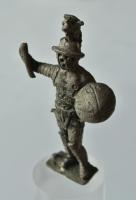 STE-4451 - Statuette : gladiateurargentStatuette figurant un gladiateur, en subligar, casqué , s'appuyant de sa main droite sur une lance et protégé par un petit bouclier circulaire d'où émerge la pointe de sa dague. Son bras est protégé par des bandes (métalliques ?). La figurine est solidaire d'une plaque rectangulaire.