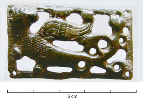 BAC-6008 - Boucle à chape ajourée rivetée : vouivrebronzeBoucle à chape rectangulaire, décor en relief ajouré et riveté aux quatre angles, représentant un animal fantastique, un serpent ailé  (ou vouivre) vers la gauche, la tête retournée en arrière.