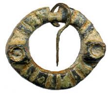 FER-7011 - FermailbronzeAnneau plat, pourvu d'une encoche pour l'articulation d'un ardillon libre, orné de deux cabochons pour pierre ou émail, et barré transversalement d'encoches sans doute émaillées.