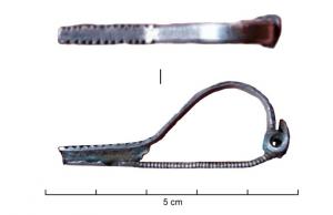 FIB-41409 - Fibule à ressortargentFibule à arc rubané, venant s'enrouler vers la tête pour former un ressort à 4 spires et corde externe. Le pied est plat, et orné de deux séries d'excisions latérales.